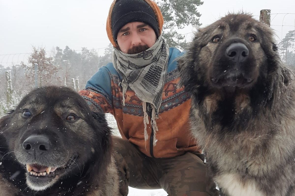 Marcin Pakuła z dwoma psami w zimowym lesie
